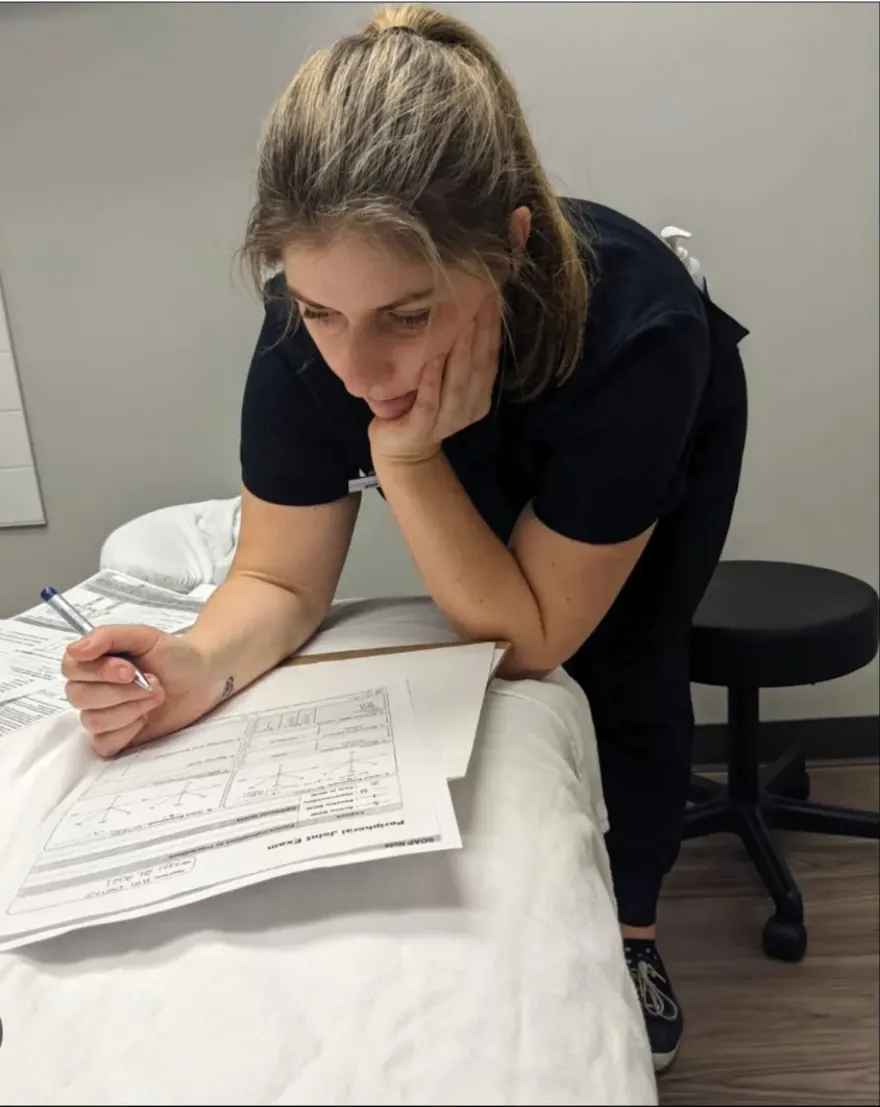 Sarah Dennis reviewing a joint assessment form on a treatment table